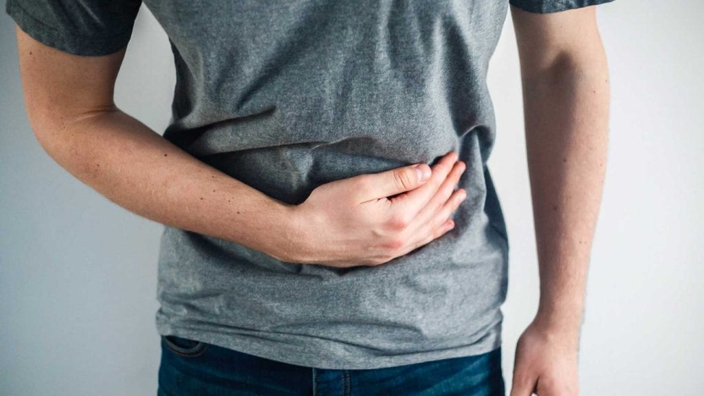 Man holding his stomach, showing discomfort from digestive disturbance or Irritable Bowel Syndrome (IBS)