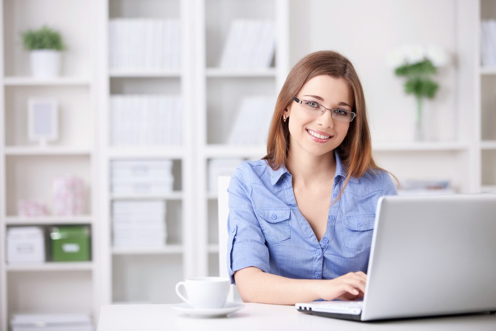 Woman working on a laptop in a modern office, representing virtual health appointments