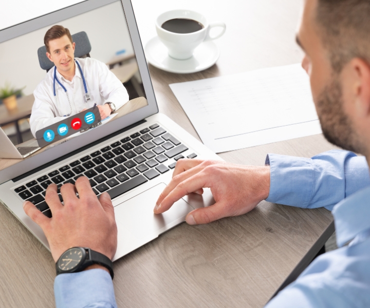 Online doctor consultation via video call on laptop at home office desk