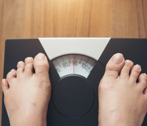 Person standing on a scale checking their weight, highlighting progress with metabolic reset