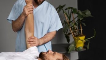 Chiropractor assists patient with arm and shoulder mobility exercise during chiropractic care session